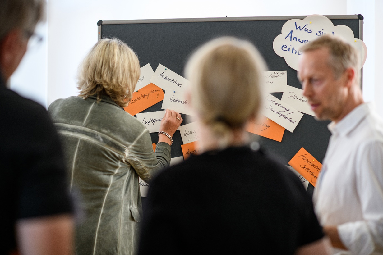 Mehrere Personen stehen vor einer Pinnwand