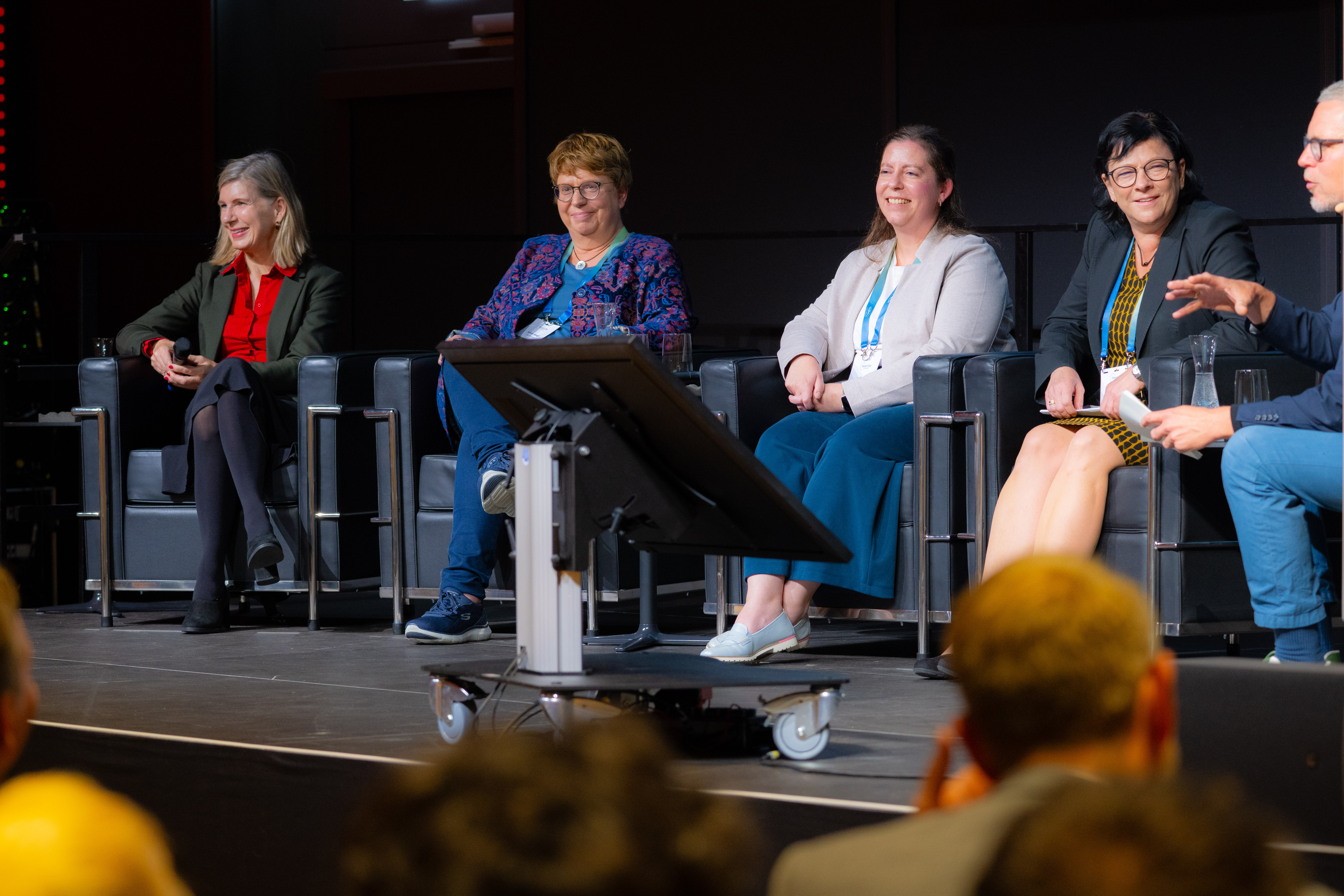 Fünf Menschen sitzen auf einem Podium und diskutieren