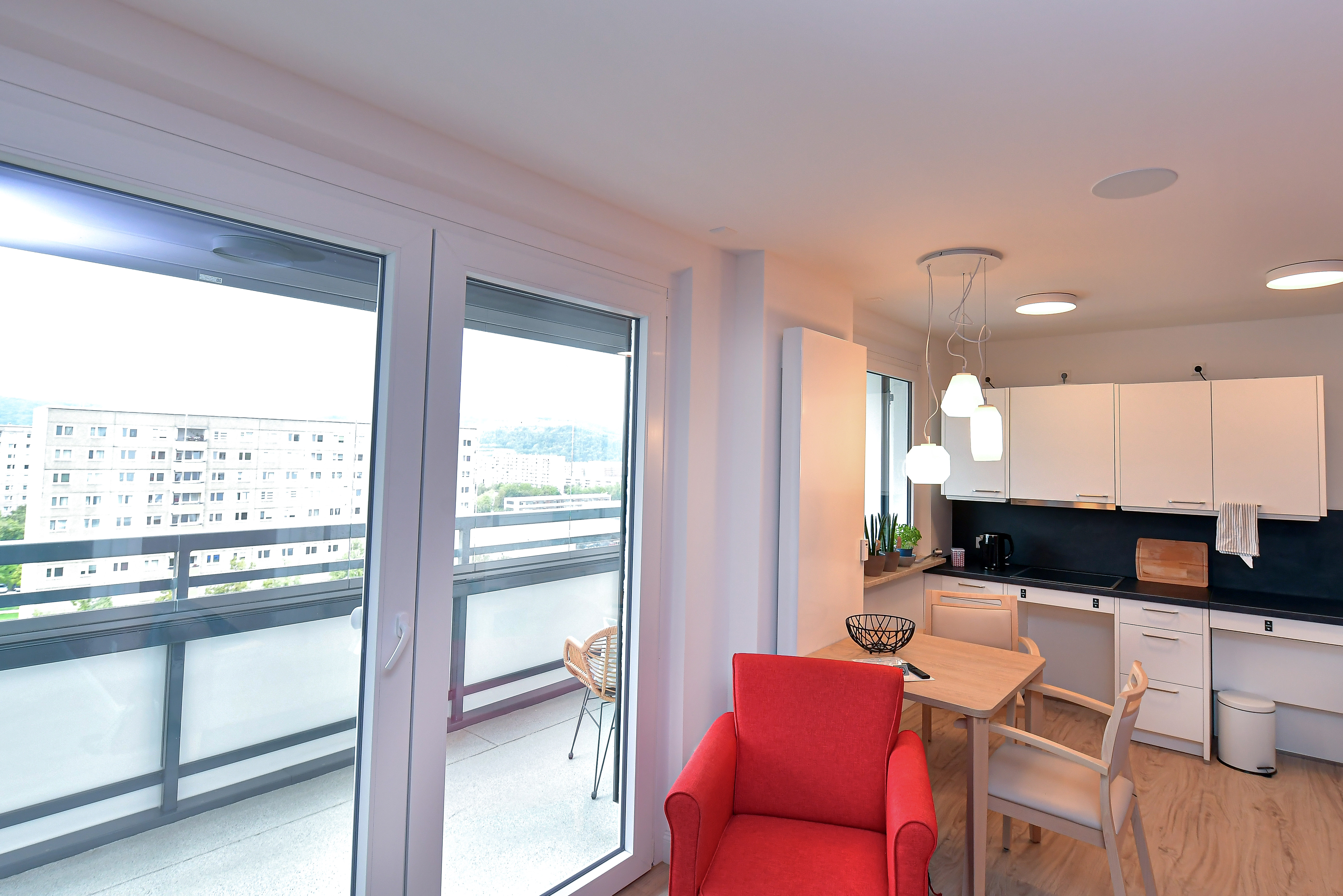 modernes Appartment mit Küchenzeile, man sieht den Blick auf den Balkon.