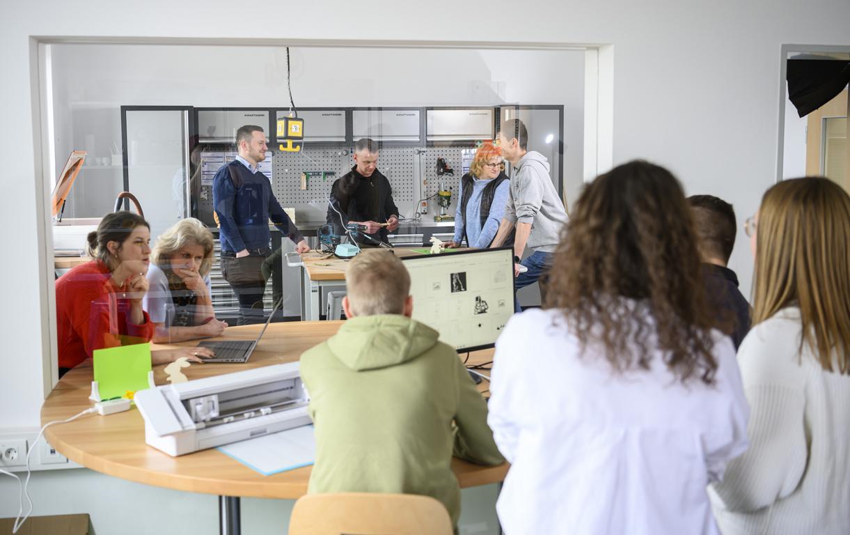 Menschen von hinten fotografiert arbeiten an verschiedenen Geräten. 