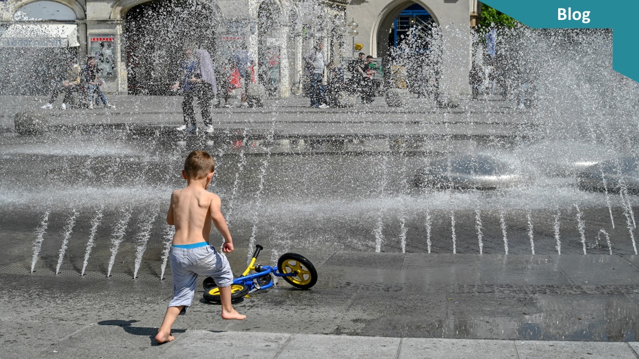 Ein kleiner Junge spielt im Sommer an einem Springbrunnen