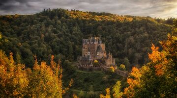 Blick auf Burg Eltz bei Abendstimmung und umgeben von goldener Herbstfärbung